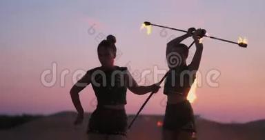 火舞者对抗日落。 在<strong>舞蹈表演</strong>中，一个年轻的女人用她的火箍在夕阳下摆姿势。